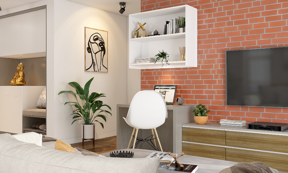 1 bhk flat living room designed with a brick cladding wall, a TV unit, and a small study nook looks classy.