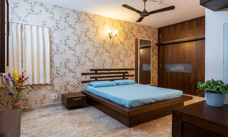 A master bedroom with a dark wood wardrobe, designed in Suncity Bellandur by DesignCafe