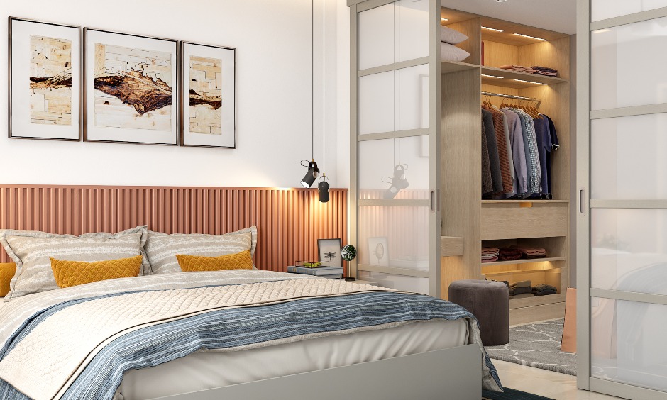 A bed with an extended headboard and hanging lights and a walk in wardrobe in a 3bhk flat interior design