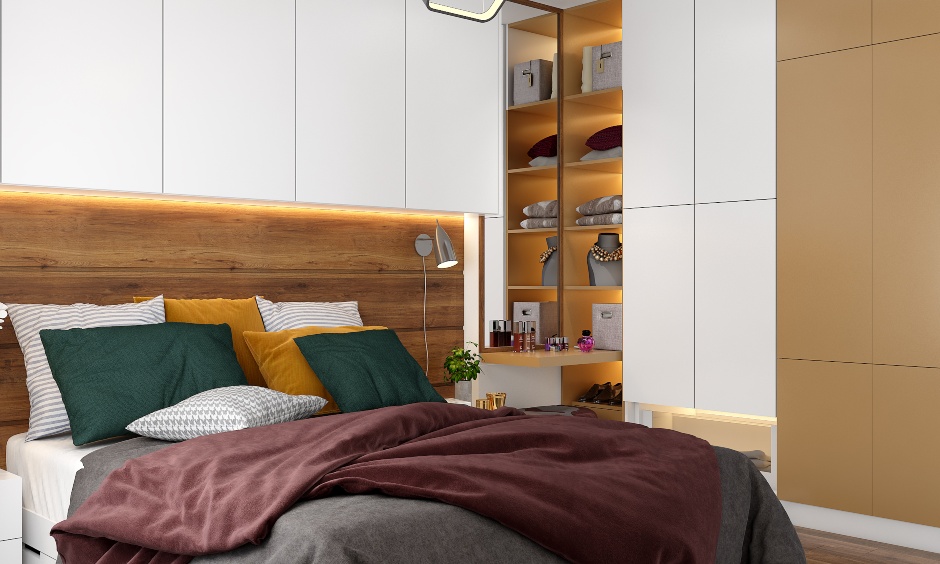 A guest bedroom with a wooden headboard and overhead cabinet for 3bhk flat interior design