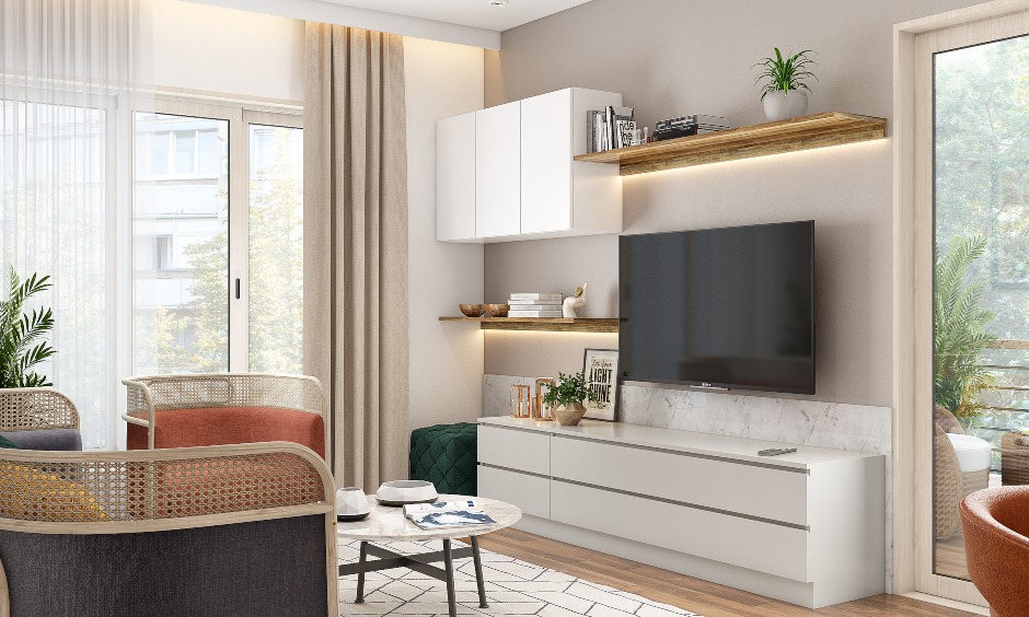 A sideview of a tv unit with chair sofas, pull to open drawers and overhead cabinets in a 3bhk duplex interior design