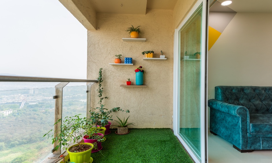 Balcony designed with refreshing turf grass carpet, some floating wall shelves and some beautiful potted plants by 4low budget interior designers in mumbai