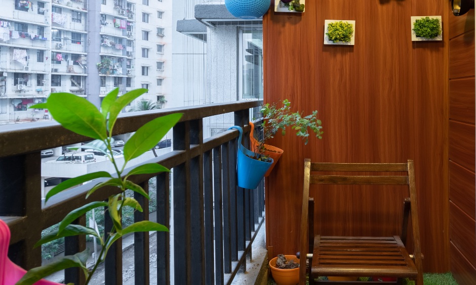 Balcony designed with wooden wall panelling, turf carpet, hanging planters designed by interior stylist mumbai