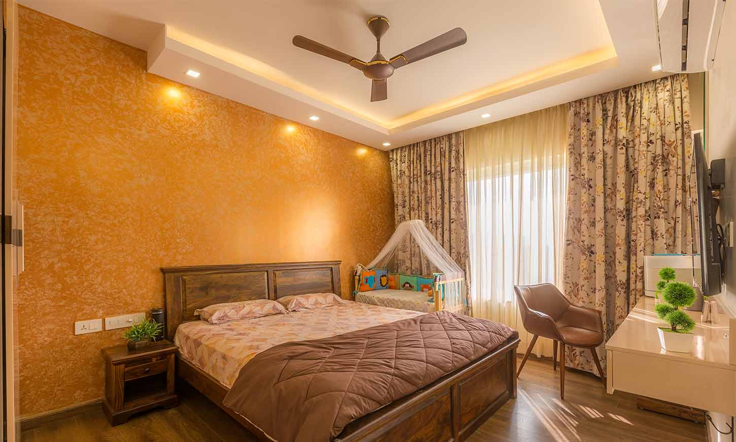 Bedroom interior design bangalore for rohan iksha apartment with a tv unit and a baby cot beside it