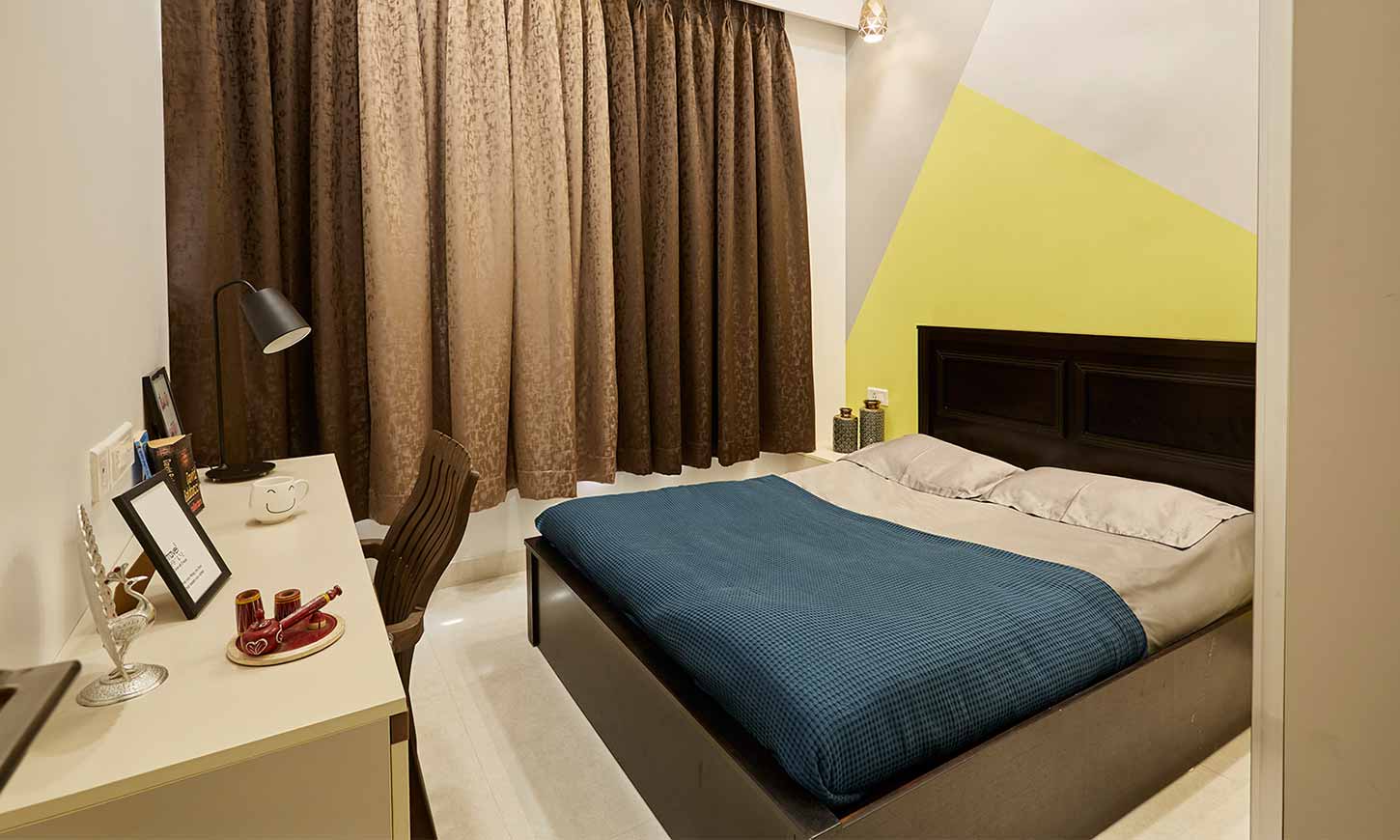 Bedroom interior design in mumbai with a working table and brown curtains