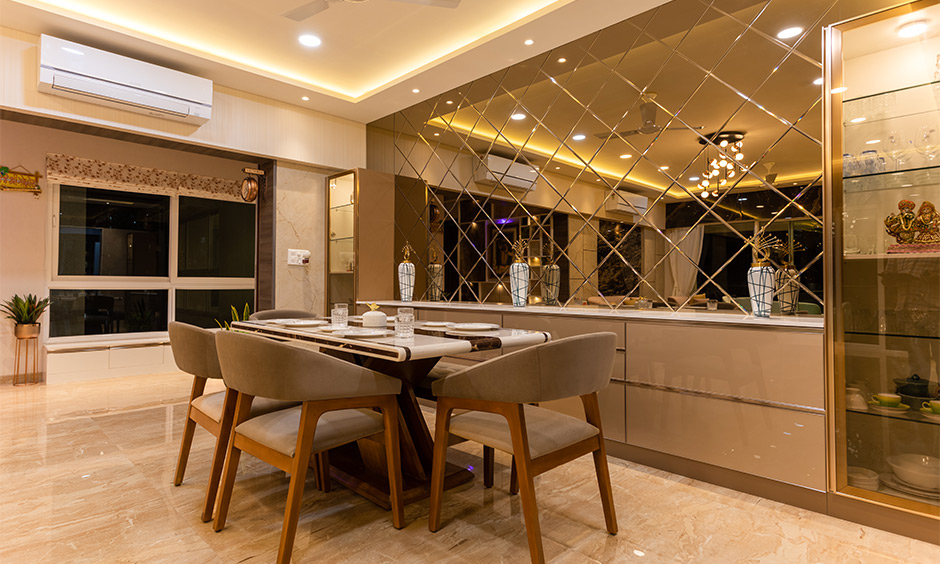 Best home interior designer in mumbai where the dining room's interior design is highlighted with a mirrored wall facing the table.