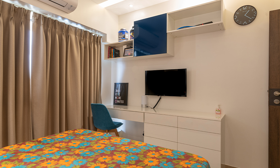 Best interior design in mumbai with a bedroom with study table and overhead storage