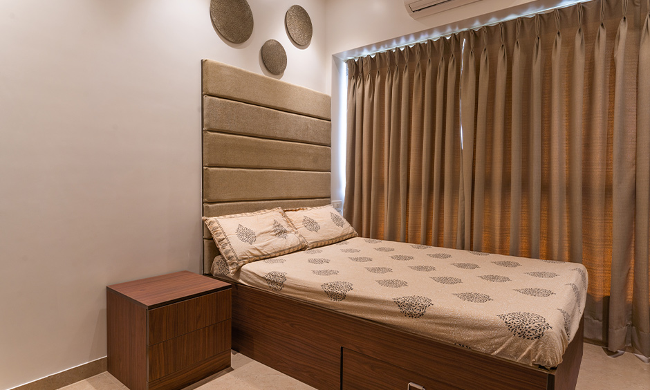 A bedroom with a bed and a bedside table designed by good interior designers in mumbai