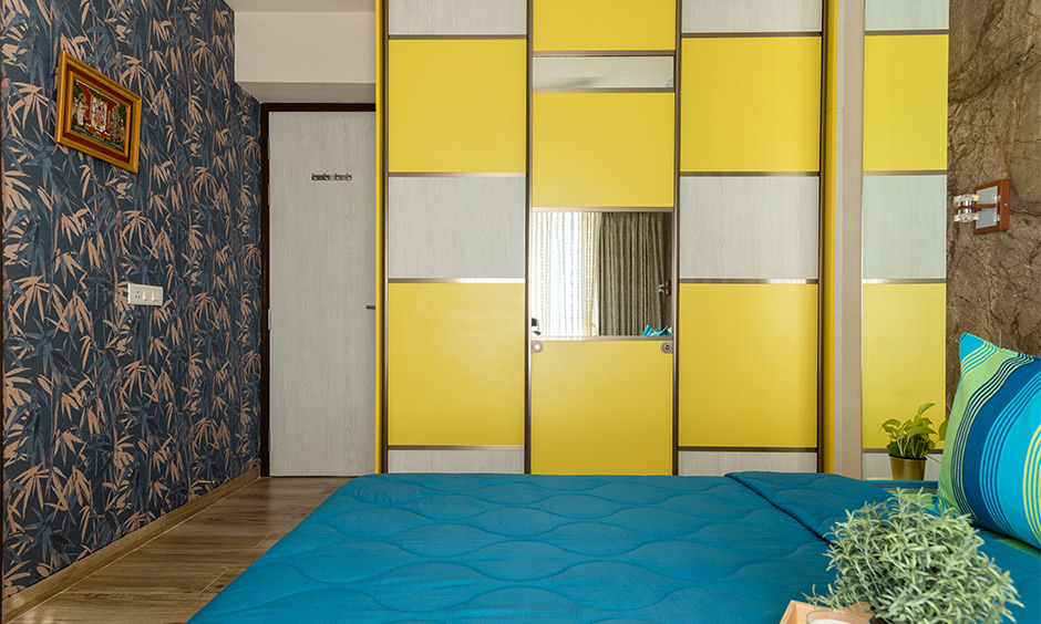 Interior designers in south mumbai where the second bedroom has a floor-to-ceiling wardrobe in yellow with a sliding door mechanism
