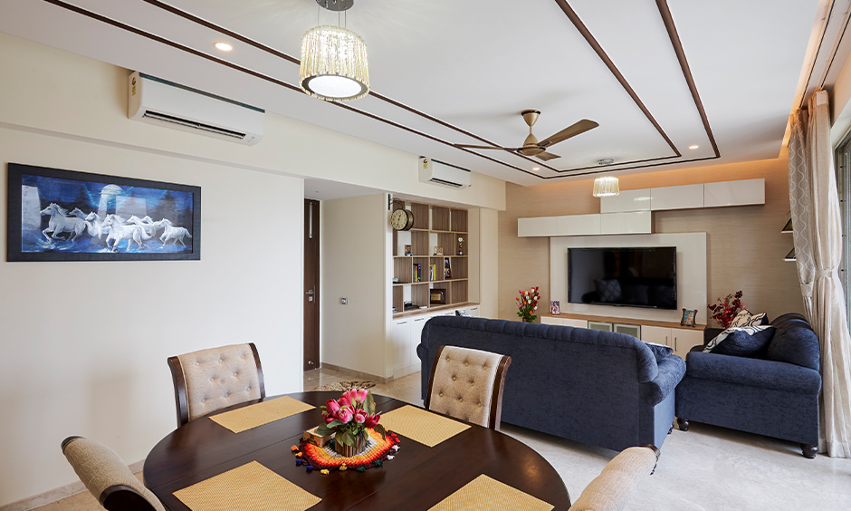 Living room interior designed with tv showcase unit and round dining table by leading interior designers in mumbai
