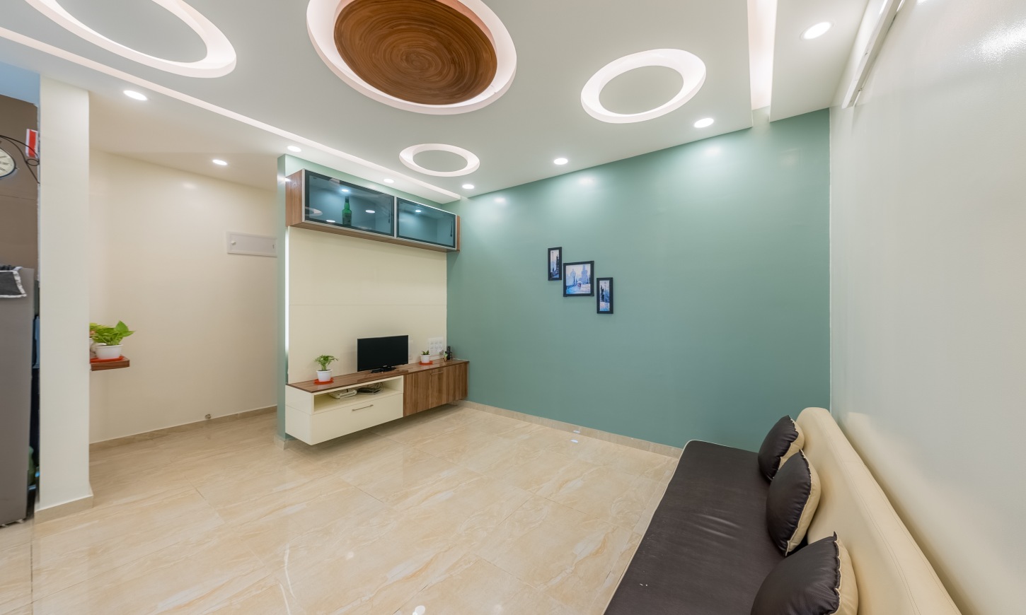 A living room designed for a 2 BHK apartment in Sarjapur Road with a TV unit and glass cabinet