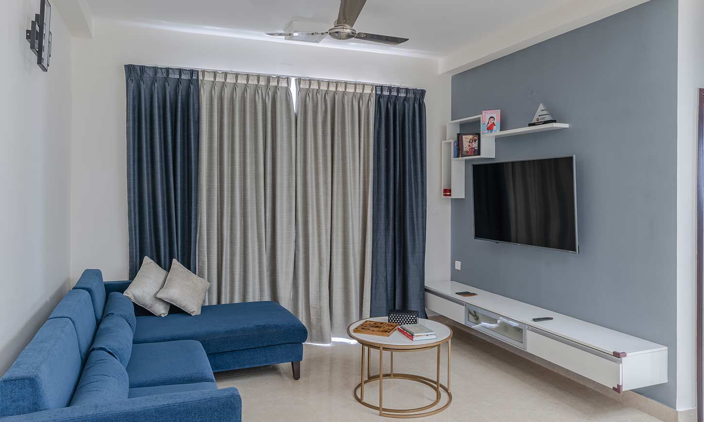 Living room interior design bangalore with a tv unit, sofa and curtains designed for prestige falcon city interior