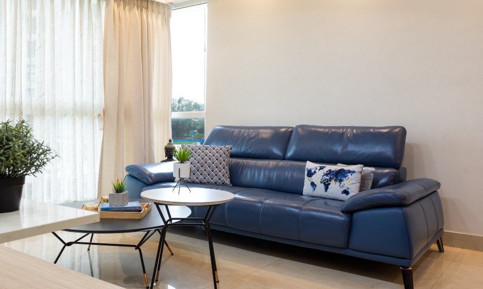 Living room is designed with a comfortable three-seater leather sofa by interior design company in mumbai