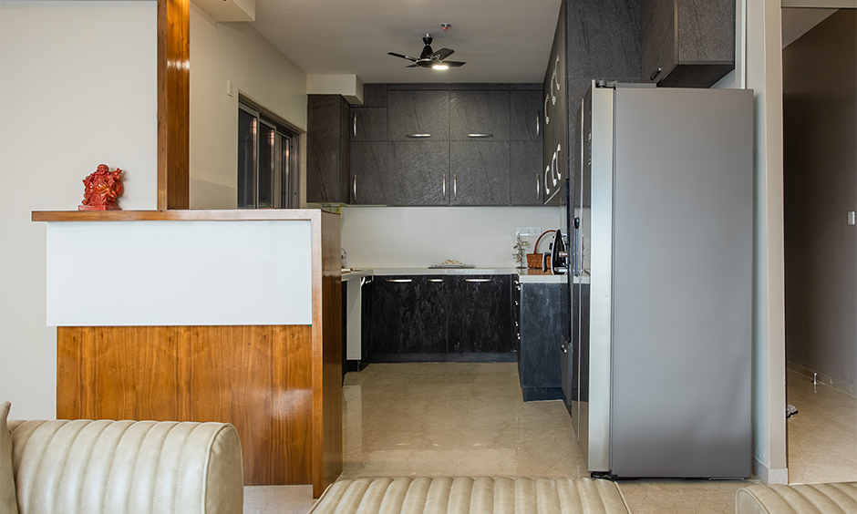 Mumbai home interior design with open kitchen with grey overhead and base cabinets and a black granite countertop