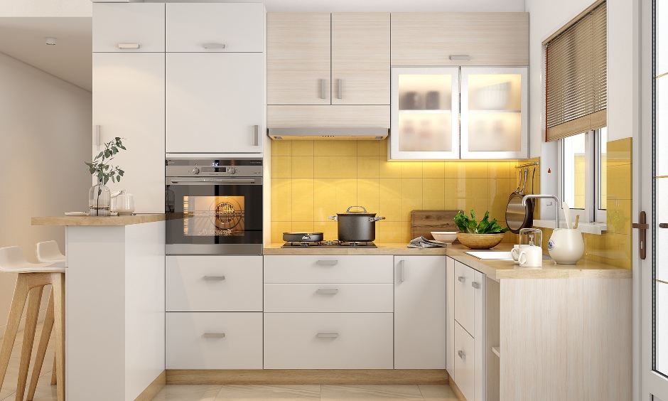 Small 2bhk kitchen designed with built-in microwave and cabinets finished in light pink and white laminate
